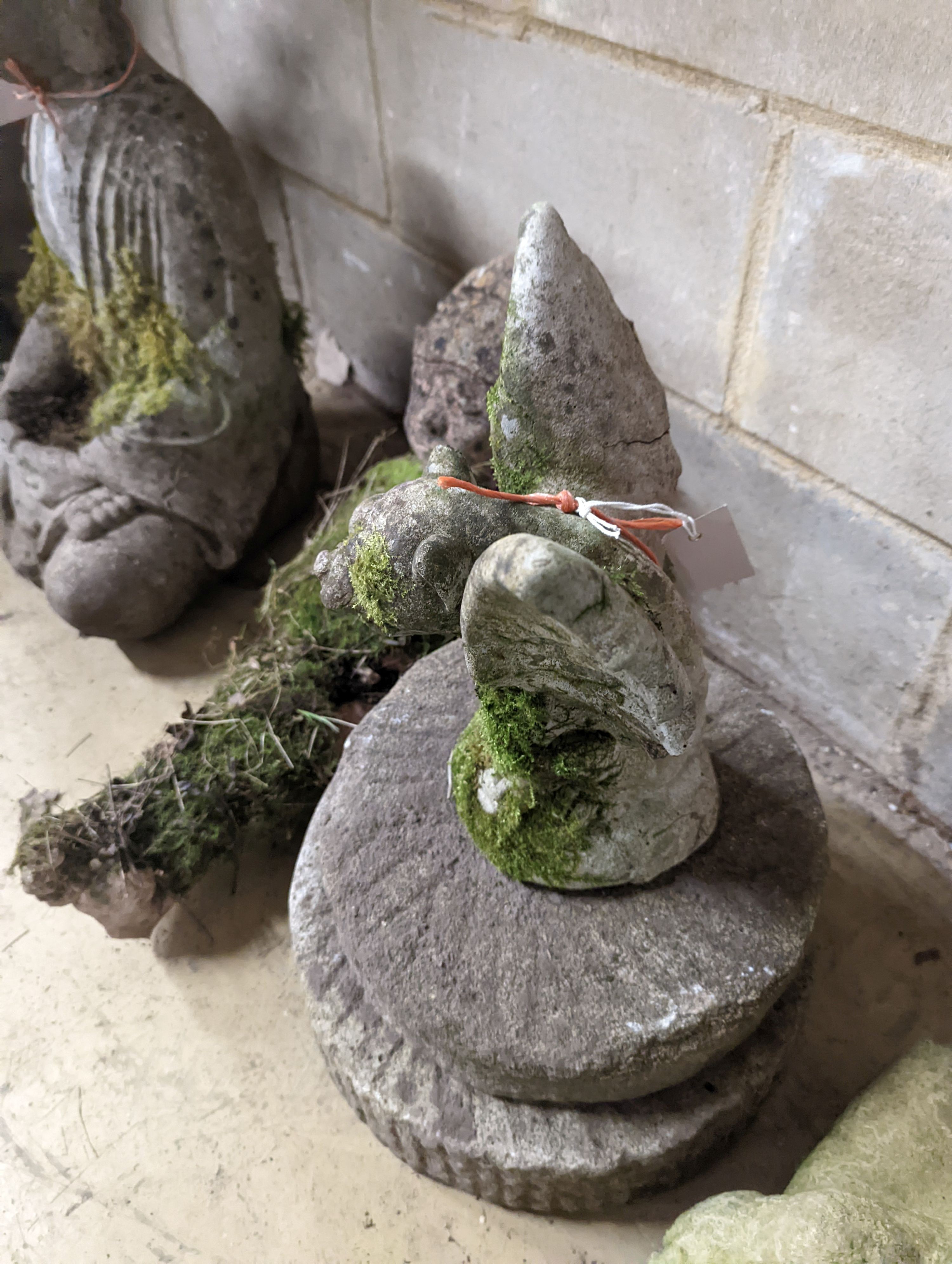 Two small circular mill stones, a reconstituted stone gargoyle and a terracotta reclining pixie garden ornament